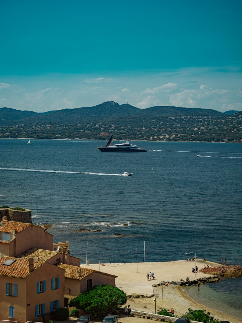 A yacht sails across a serene, blue sea.